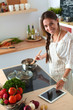 © lenets_tan - Young woman using a tablet computer to cook in her kitchen