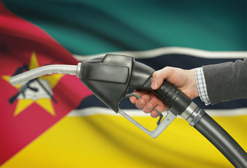 Fuel pump nozzle in hand with national flag on background - Mozambique