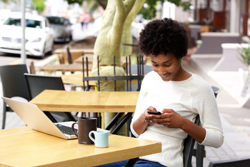 Wall Mural - African woman reading text message on mobile phone at a cafe