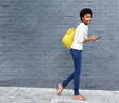 © mimagephotos - Cheerful african woman walking on street with mobile phone