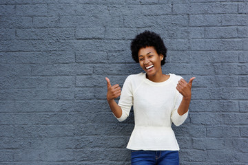 Wall Mural - Smiling young african woman with thumbs up sign