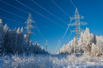 Wall Mural - The group of high-voltage electricity power pylons over blue sky and covered by snow