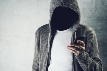 faceless hooded person using mobile phone, identity theft concep