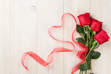 Red Roses And Heart Shape Ribbon Over Wood