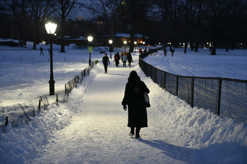 Woman strolling through a snowy park at night