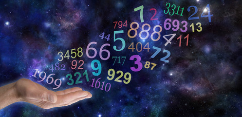 What do your Numbers mean - male hand palm up with a group   of random multicolored transparent numbers floating up and away on a wide deep space background with copy space