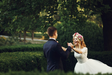 Wall Mural - Happy young bride in white dress running towards groom outdoors