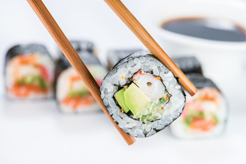 Sticker - close up of chopsticks taking portion of sushi roll on the table