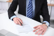 © rogerphoto - Young business man signs contract sitting at the desk in office