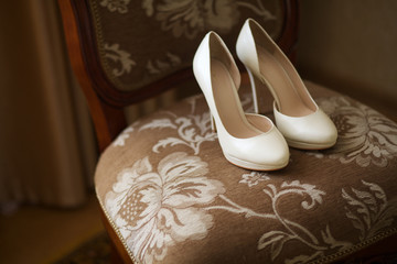 elegant bride's white shoes on a chair