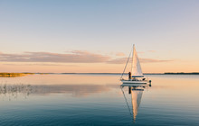 Sailing Boat On A Calm Lake With Reflection In The Water. Serene Scene Landscape.
