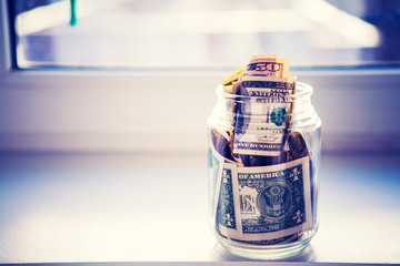 a glass jar with money is isolated on a background a window