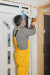 © sima - Worker installing wooden door, using polyurethane foam