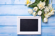 White tulips and narcissus flowers  and empty blackboard  on blu