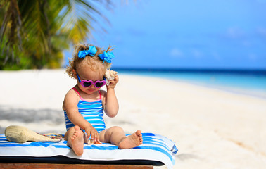 cute little girl listening to shell on beach