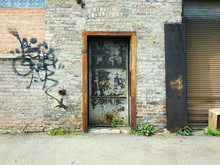 Doorway On Brick Wall In Urban Setting With Graffiti - Landscape Photo