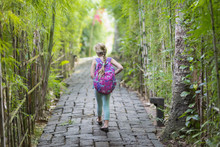 Caucasian Girl Walking On Stone Path Among Bamboo Trees