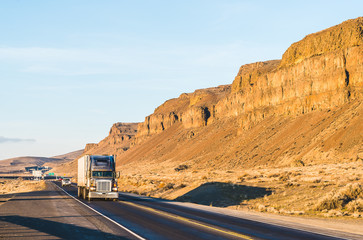 a big truck driving in the sunset with mountain background.