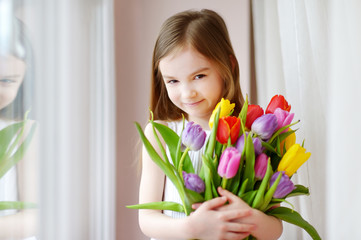 Wall Mural - Adorable smiling little girl with tulips