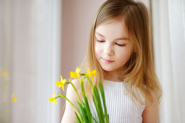 Wall Mural - Adorable smiling little girl holding daffodils