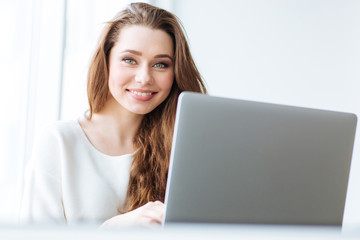 Canvas Print - Cheerful woman sitting at the table with laptop