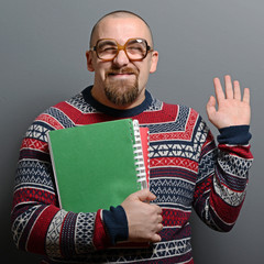 Wall Mural - Portrait of a nerd holding book with retro glasses against gray