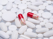 Many white tablets and two red capsules transparent. One can see the contents of the capsules - red and white beads. The antiviral drug