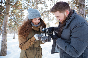 Poster - Happy couple drinking hot tea in winter park