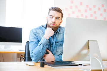 Wall Mural - Pensive modern designer sitting on workplace and thinking