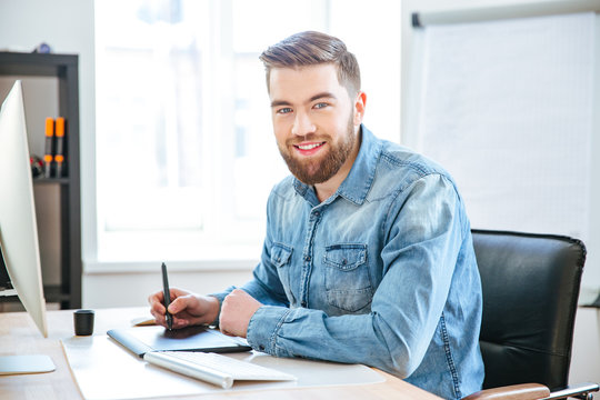 Happy designer working using pen tablet with stylus in office