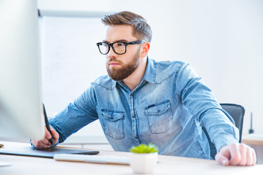 Serious concentrated man designer drawing with graphic pen tablet
