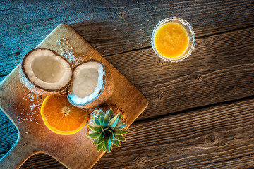 fruit pineapple smooties with coconut and orange on wooden table, picture with blue light and postprocess