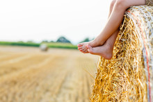 Little kid boy sitting on hay bale in summer
