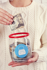 Wall Mural - Woman hands with money in glass jar, close up