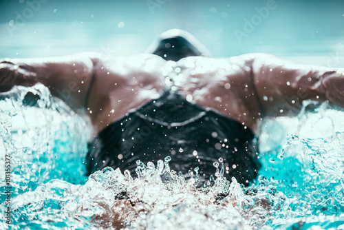 Zdjęcie XXL Mistrz skokowy pływacki w akcji. Potężny ciąg do przodu. Strzał z tyłu, skupia się na fali wody za pływakiem