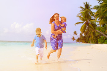 Wall Mural - happy little boy with mother and sister running on beach