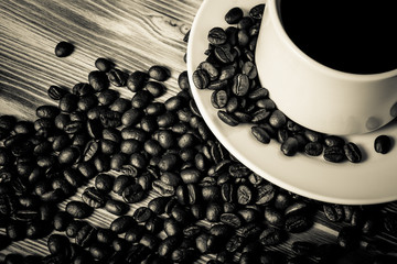 Coffee beans and coffee in white cup on wooden table for backgro