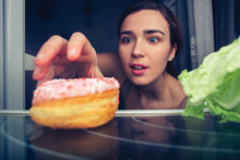 Hungry Cute Female Reaches For Donut At Night Near Fridge