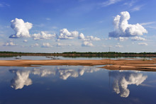 Symmetric Reflection Of Dense Clouds And Blue Sky In The Smooth River With Sandy Island