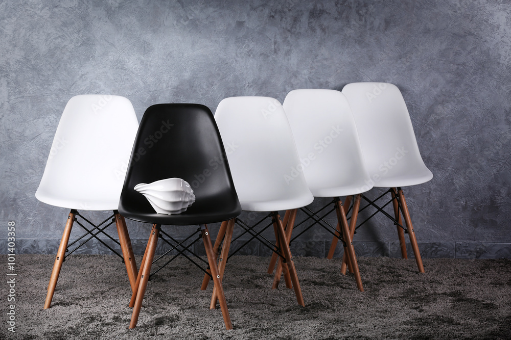 Stylish conception with white and black chairs on grey background