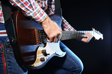 Wall Mural - Young man playing on electric guitar close up