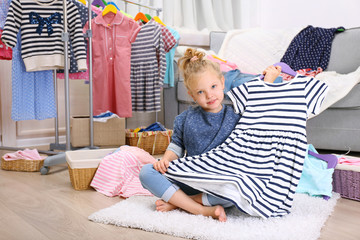 Little girl in the room with a lot of new clothes