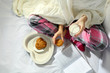 Woman in pajamas reading a book and drinking milk with cookies on her bed