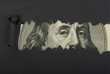 Benjamin Franklin macro peeking through torn black paper