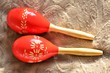 Couple of bright red wooden maracas on brown background in sunny day