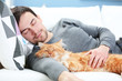 © Africa Studio - Young man with fluffy cat lying on a sofa