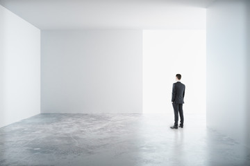 Wall Mural - Man standing in a white room and looking to the blank wall, mock