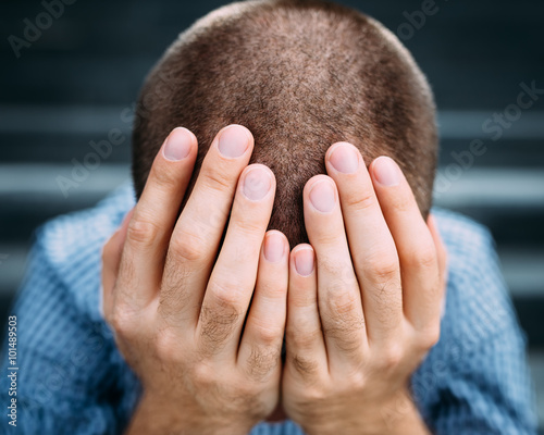 Fotografía Closeup portrait of despaired young man covering his face with hands