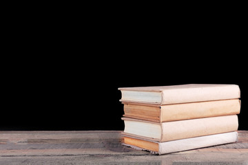 Sticker - Stack of books on wooden table,  black background