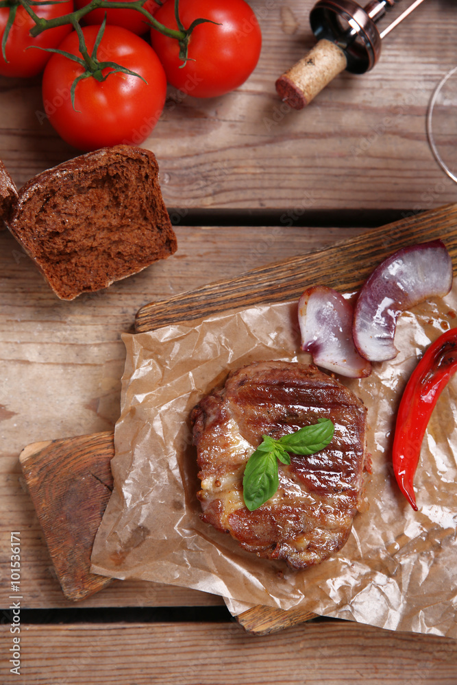 Roasted beef fillet and vegetables on cutting board, on wooden background